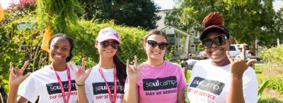 Four students wearing SOUL Camp t-shirts pose in a garden, giving the UL fleur-de-lis hand sign